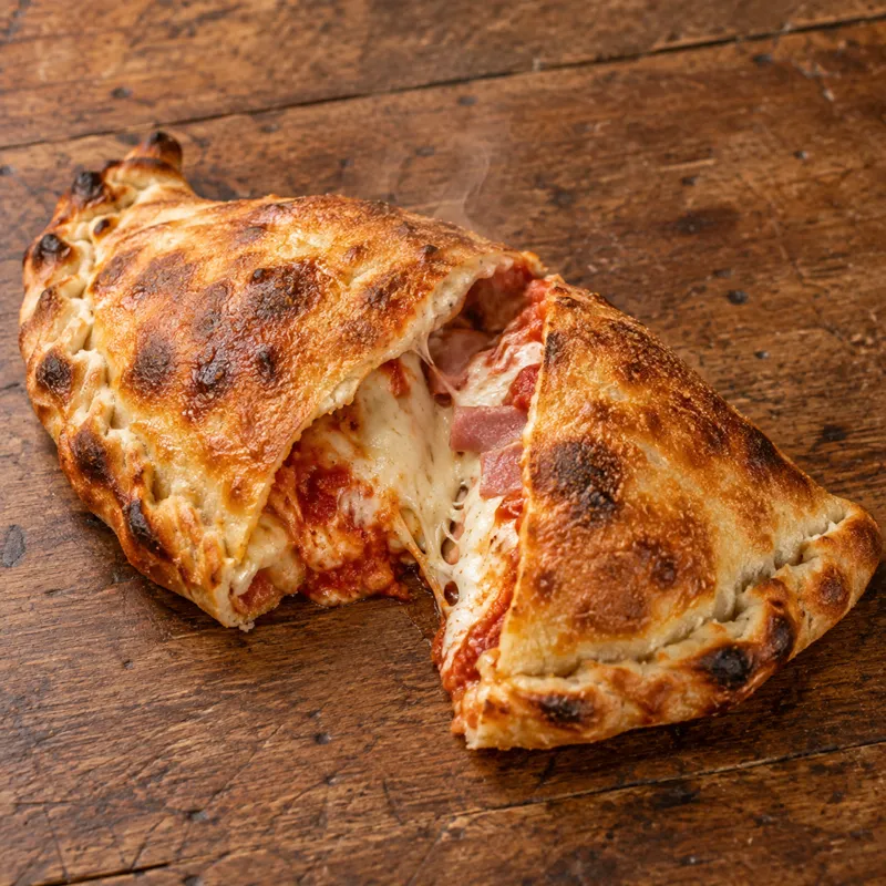 Gylden calzone skåret op, så fyldet ses, set skråt oppefra